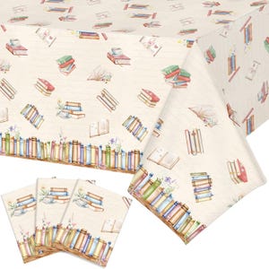 May include: A cream-colored tablecloth and matching napkins featuring a repeating pattern of stacks of colorful books, open books, and teacups. The bottom edge of the fabric displays a continuous row of upright books in various colors.