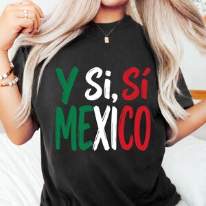 Può includere: Una t-shirt nera a maniche corte con la scritta Y Si, Sí MEXICO stampata in stile pennellata. Le lettere sono colorate in verde, bianco e rosso, imitando i colori della bandiera messicana, centrate sulla parte anteriore del capo.