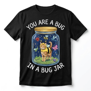 Könnte beinhalten: Ein schwarzes T-Shirt mit einer Grafik einer rot getigerten Katze in einem Bienenkostüm in einem Glas. Das Glas enthält verschiedene Insekten wie einen Marienkäfer, eine Biene, eine Libelle, einen Schmetterling und eine Heuschrecke. Text: YOU ARE A BUG IN A BUG JAR.