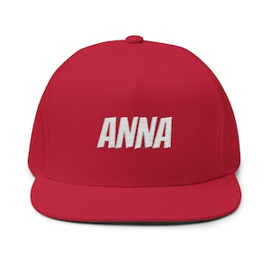 Op de afbeelding: Rode baseballpet met een platte klep, met de naam "ANNA" geborduurd in witte hoofdletters. De pet heeft een gestructureerde pasvorm en een platte klep.