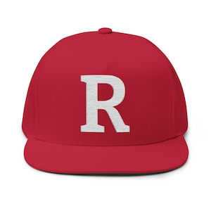 Könnte beinhalten: Eine rote Baseballkappe mit flachem Schirm und einem weißen, gestickten Buchstaben "R" auf der Vorderseite. Die Kappe hat eine strukturierte Passform und einen flachen Schirm. Der Hut ist einfarbig rot.