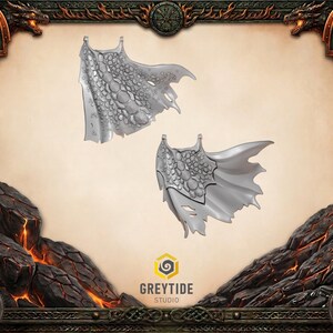 Può includere: Due miniature di ali di drago argentate con una texture a scaglie e una forma a mantello. Le ali hanno bordi frastagliati. Lo sfondo presenta un bordo decorativo con motivi di drago e scudo e il testo "GREYTIDE STUDIO".