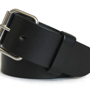 May include: A black belt featuring a smooth, matte finish and a silver-toned metal double-prong buckle. The belt strap is constructed from a solid, uniform material with a rounded tip and a single matching black leather keeper loop near the buckle.