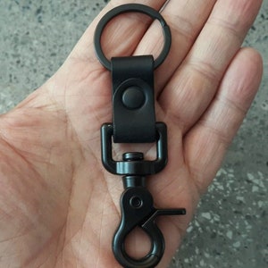 May include: Black leather key chain with a metal ring and a black metal clip.
