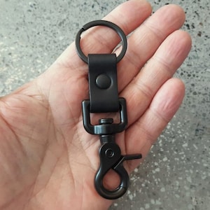 May include: Black leather key chain with a metal ring and a black metal clip.