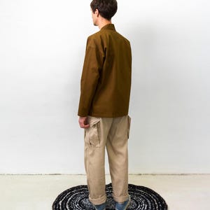Puede incluir: Una camisa marr&oacute;n de manga larga con cuello mao y pantalones cargo de color beige con bolsillos laterales. Los pantalones tienen un corte recto con dobladillos vueltos, combinados con zapatillas bajas azules y blancas con suela de goma.