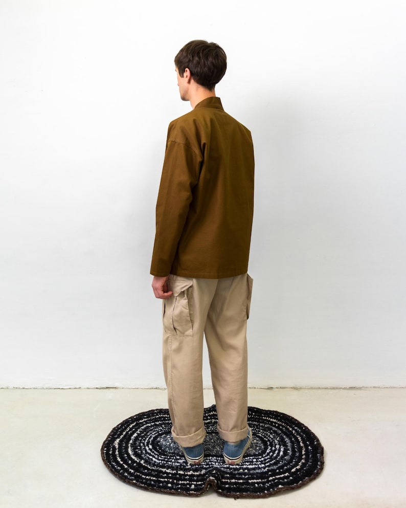 Puede incluir: Una camisa marr&oacute;n de manga larga con cuello mao y pantalones cargo de color beige con bolsillos laterales. Los pantalones tienen un corte recto con dobladillos vueltos, combinados con zapatillas bajas azules y blancas con suela de goma.