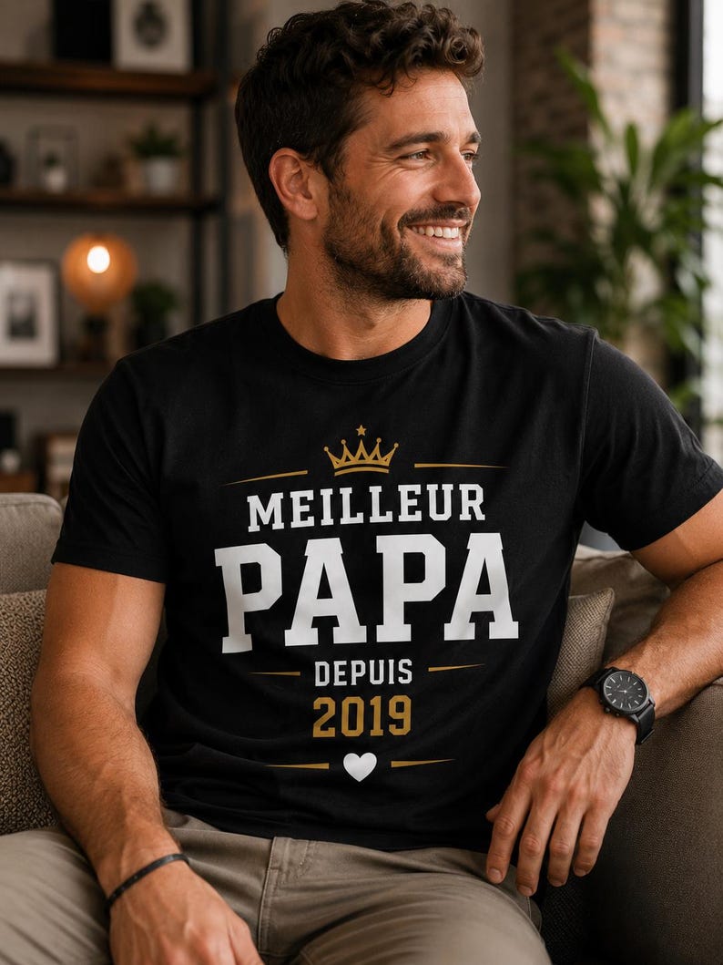 May include: A black short-sleeved t-shirt featuring a gold crown graphic above the white text "MEILLEUR PAPA" and the gold text "DEPUIS 2019" with a small white heart icon centered below the year, all printed on the front of the garment.