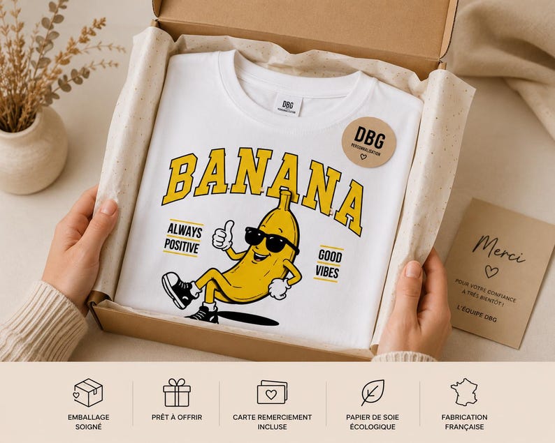 K&ouml;nnte beinhalten: Ein wei&szlig;es T-Shirt mit einer gelben Cartoon-Banane, die eine schwarze Sonnenbrille tr&auml;gt, einen Daumen hoch zeigt und sitzt. Der Text BANANA steht in gro&szlig;en gelben Buchstaben dar&uuml;ber, mit ALWAYS POSITIVE und GOOD VIBES an den Seiten.