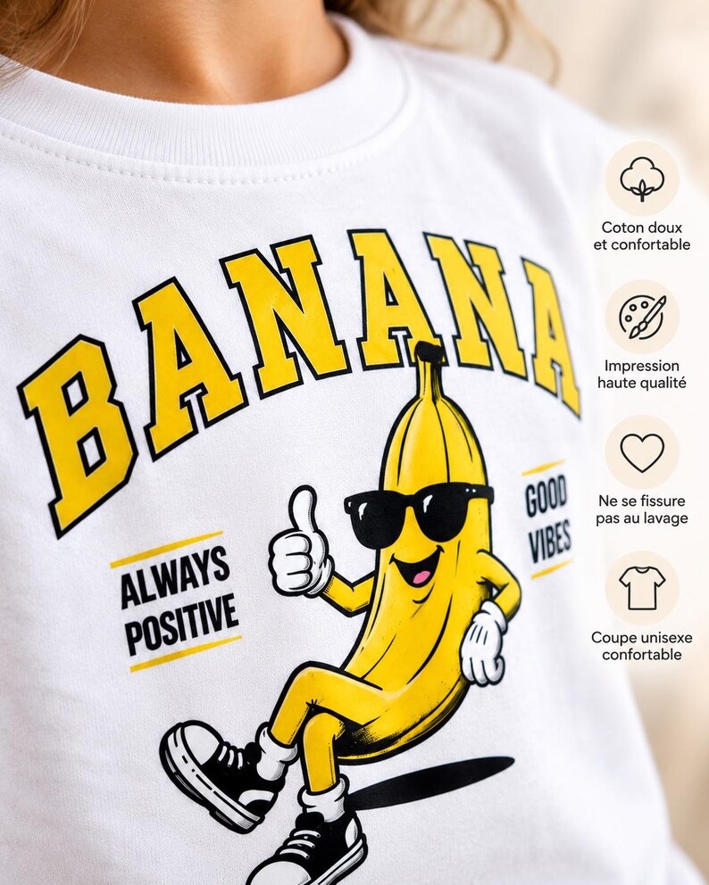 K&ouml;nnte beinhalten: Ein wei&szlig;es Sweatshirt mit Rundhalsausschnitt und einer gro&szlig;en gelb-schwarzen Grafik einer Cartoon-Banane mit Sonnenbrille und schwarzen Turnschuhen, die den Daumen hochh&auml;lt. Der Text lautet BANANA, ALWAYS POSITIVE und GOOD VIBES.