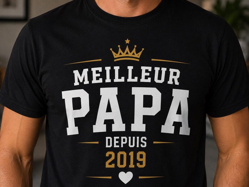 May include: A black short-sleeved t-shirt featuring a graphic print with a gold crown above the white text MEILLEUR PAPA. Below this, the text DEPUIS 2019 appears in gold, followed by a small white heart centered between two horizontal gold lines.