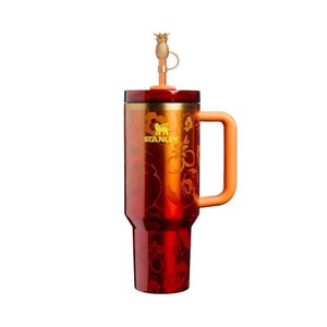 May include: A deep red Stanley tumbler featuring a metallic finish with a subtle floral pattern, a yellow logo, and an orange handle. The lid includes a gold-colored straw topper shaped like a pineapple, attached by a small loop to the straw.