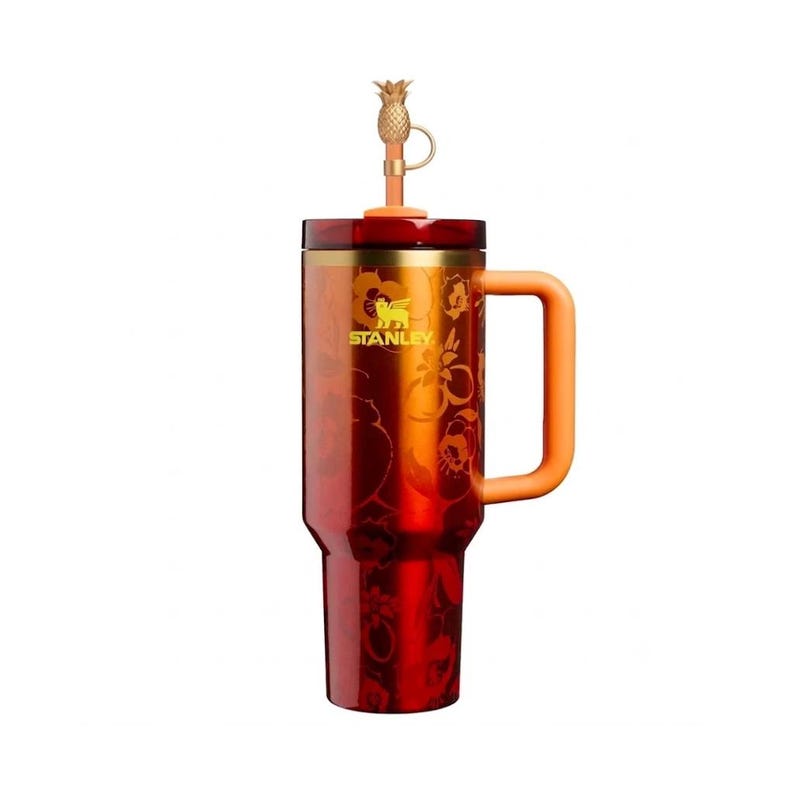 May include: A deep red Stanley tumbler featuring a metallic finish with a subtle floral pattern, a yellow logo, and an orange handle. The lid includes a gold-colored straw topper shaped like a pineapple, attached by a small loop to the straw.