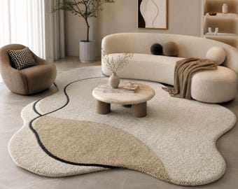 Könnte beinhalten: Ein modernes Wohnzimmer mit einem cremefarbenen, abstrakt geformten Teppich mit beigem und schwarzem Design. Ein geschwungenes Sofa, ein runder Couchtisch und ein gemütlicher Sessel vervollständigen den Raum. Der Raum ist in neutralen Tönen gehalten und schafft eine ruhige Atmosphäre.