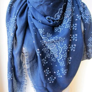 May include: A navy blue scarf with a white paisley pattern. The scarf has a fringed edge.