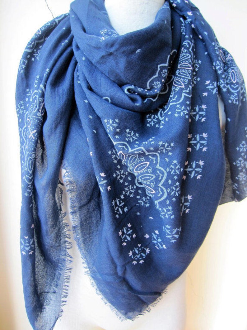 May include: A navy blue scarf with a white paisley pattern. The scarf has a fringed edge.