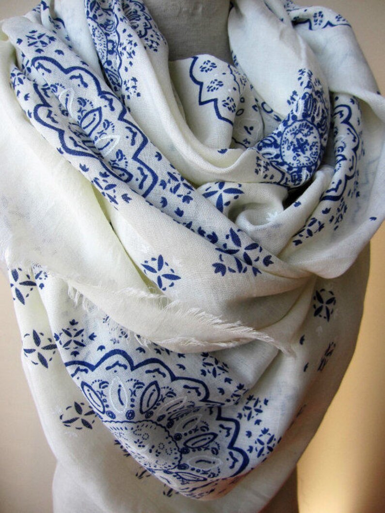 May include: White scarf with a blue paisley pattern. The scarf is made of a soft, lightweight fabric and is perfect for adding a touch of style to any outfit.