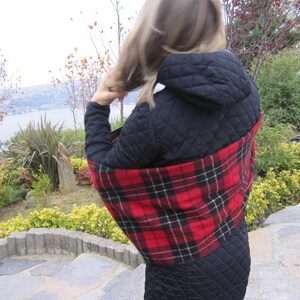 May include: A black quilted jacket with a red and black plaid scarf. The scarf is wrapped around the neck and shoulders.