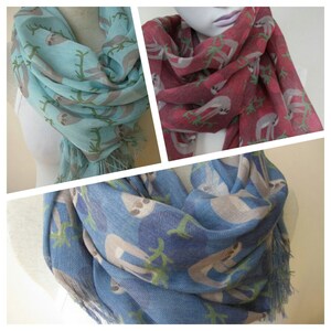 May include: Three different colored scarves with a sloth print. The scarves are blue, red, and light blue. Each scarf has a fringe on the bottom.