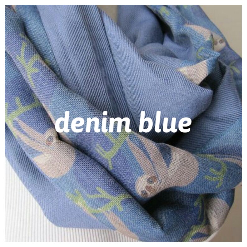 May include: A denim blue infinity scarf with a pattern of sloths hanging from branches. The scarf is soft and comfortable and perfect for keeping warm in the winter.