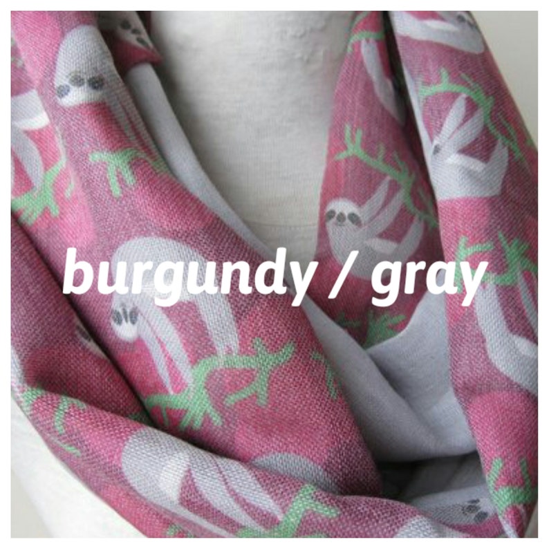 May include: Burgundy and gray infinity scarf with a sloth print. The scarf is made of a soft, comfortable fabric and features a repeating pattern of sloths hanging from branches.