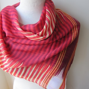 May include: A red and white striped scarf with a yellow stripe. The scarf is made of a soft, lightweight fabric and is perfect for adding a pop of color to any outfit.