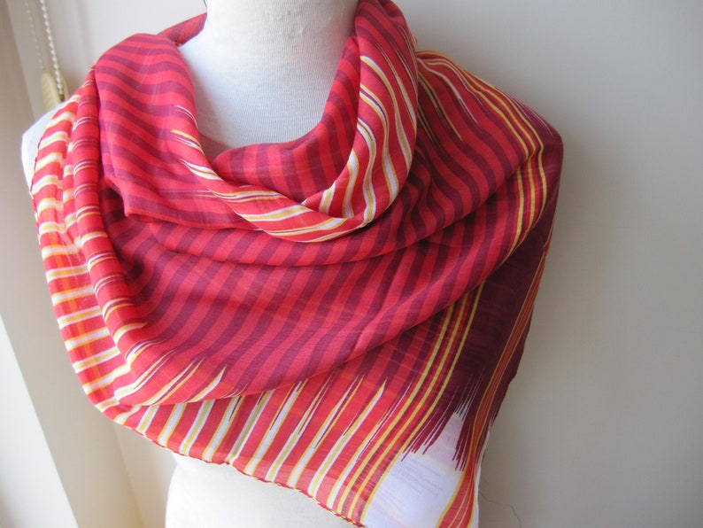 May include: A red and white striped scarf with a yellow stripe. The scarf is made of a soft, lightweight fabric and is perfect for adding a pop of color to any outfit.