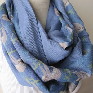 May include: A blue infinity scarf with a pattern of sloths on a branch. The scarf is made of a soft, comfortable fabric and is perfect for keeping warm in the winter.