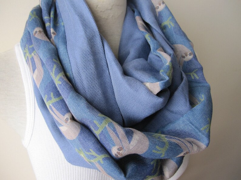 May include: A blue infinity scarf with a pattern of sloths on a branch. The scarf is made of a soft, comfortable fabric and is perfect for keeping warm in the winter.