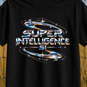 May include: A black short-sleeved t-shirt featuring a metallic, chrome-effect graphic on the chest. The design displays the text SUPER INTELLIGENCE SI surrounded by orbital rings and small spheres, creating a futuristic, three-dimensional appearance.