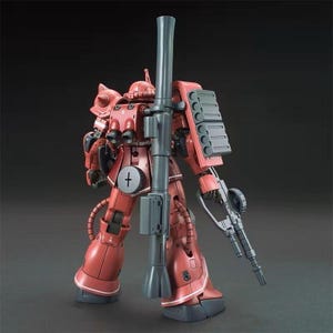 Puede incluir: Maqueta roja y gris de un traje m&oacute;vil, con un ca&ntilde;&oacute;n grande y un rifle. El modelo tiene componentes mec&aacute;nicos detallados y un s&iacute;mbolo de cruz en el pecho. El kit est&aacute; posado sobre un fondo oscuro.