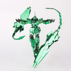 May include: A metallic green robot action figure with articulated limbs and intricate panel details. The figure has outstretched arms and is posed with large, segmented wing-like structures and a curved tail. The figure is standing on a clear stand.