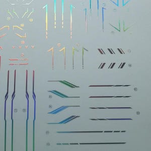 May include: A sheet of holographic vinyl stickers featuring various geometric shapes and lines in iridescent colors. Designs include angled stripes, straight lines, and stylized number markings. Ideal for crafting or customizing projects.