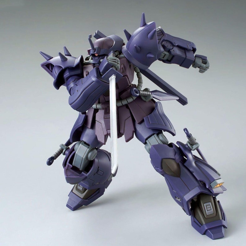May include: A dark purple robotic action figure in a dynamic combat pose, holding a silver sword vertically. The figure features spiked shoulder armor, a mono-eye sensor head, and articulated limbs with mechanical details in a matte finish.