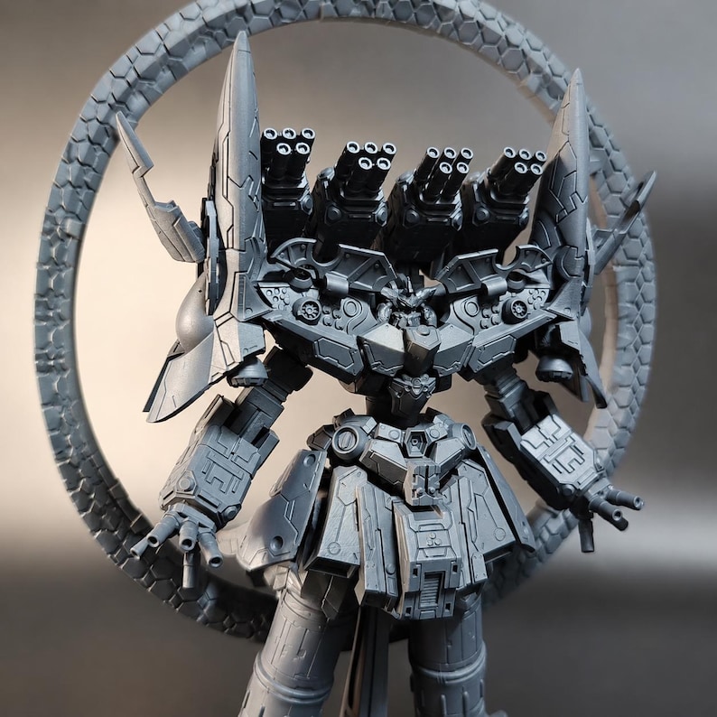 May include: A gray, detailed model of a robot with multiple cannons and a circular, textured frame. The robot has a complex design with multiple panels, spikes, and gun barrels. The model is a collectible item.