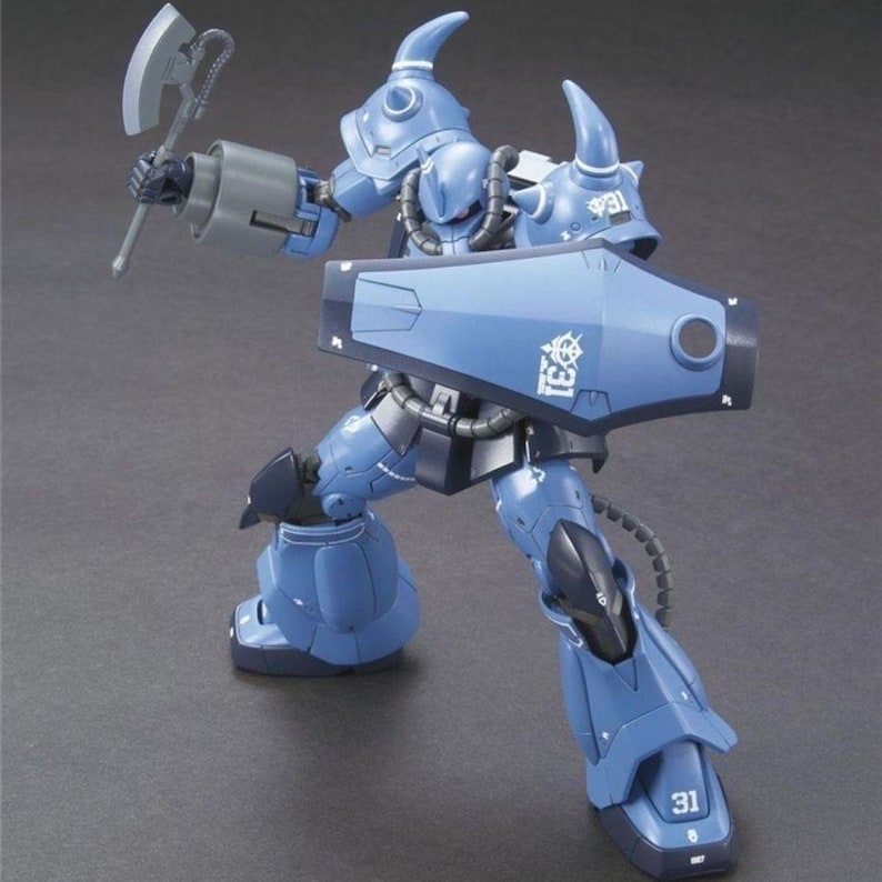 May include: A blue robot action figure with a spiked shoulder armor, holding a gray battle axe in one hand and a large blue shield in the other. The shield features the white text 31 and a white emblem. The robot has dark blue accents and joints.