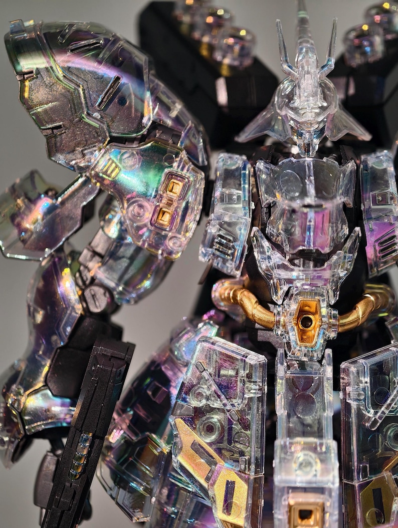 May include: A clear, iridescent robot model with intricate details. The robot features transparent armor, gold accents, and a complex internal structure. The design includes sharp angles and a futuristic aesthetic, showcasing a detailed and articulated figure.