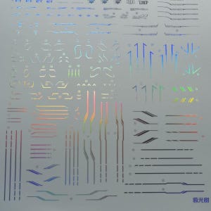 May include: A sheet of iridescent stickers with various geometric shapes and lines. The stickers feature a range of colors, including blue, green, pink, and gold. Some stickers have text, and the overall design is futuristic.