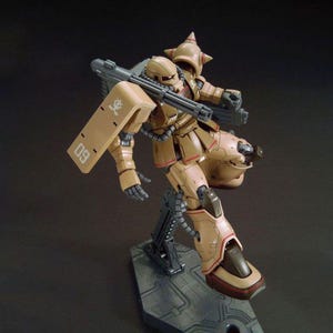 Puede incluir: Un modelo de robot marr&oacute;n y beige con un arma grande y un escudo. El robot est&aacute; posado sobre un soporte gris. El escudo tiene el n&uacute;mero "09" impreso. El robot tiene un casco puntiagudo y m&uacute;ltiples armas.