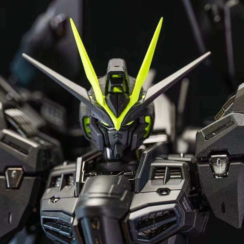 May include: Close-up of a detailed black and gray robot model with neon green accents. The robot has sharp angles, a detailed face, and prominent head crests. The model is a collectible item.