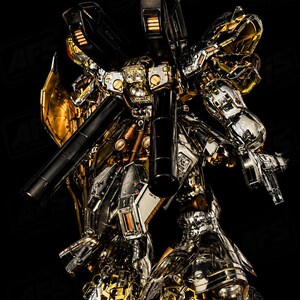 May include: A detailed, metallic robot figure with gold, silver, and black accents. The robot has multiple weapons and intricate mechanical details. The image includes the "AFS AsterForgeStudio" logo in the upper left corner.