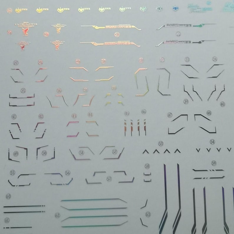 May include: A sheet of holographic stickers featuring various geometric shapes and lines in iridescent colors. The stickers include angular designs, arrows, and parallel lines, suitable for crafts or decoration.