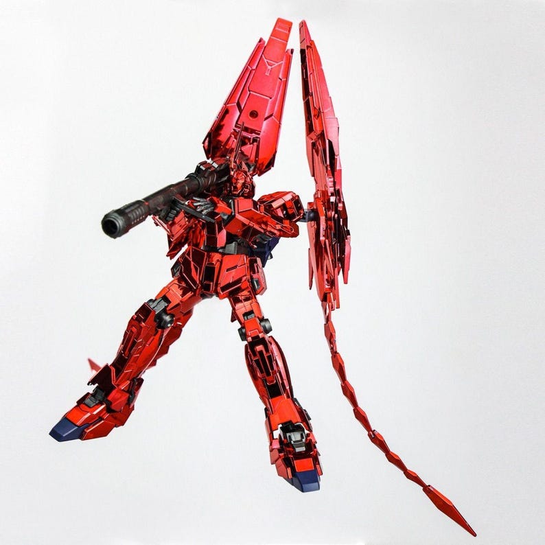 May include: A red metallic robot figure with a large gun and wing-like structures. The robot is posed dynamically, with blue accents on its feet. The figure is set against a plain white background.