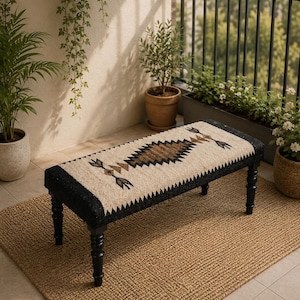 Peut inclure: Un banc rectangulaire doté de quatre pieds noirs tournés et d'une assise recouverte d'un tissu tissé. L'assise présente un motif central en losange dans des tons marron et noir, encadré par des motifs de flèches sur un fond crème.