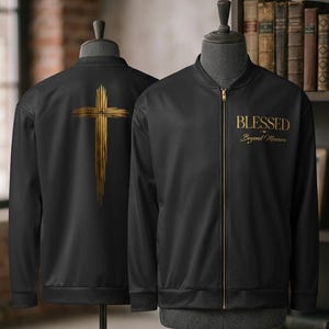 May include: A black bomber jacket featuring a gold zipper and a gold cross graphic on the back. The front displays the text BLESSED Beyond Measure in gold lettering. The jacket is displayed on two mannequins to show both the front and back views.