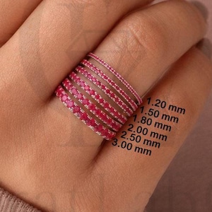 Könnte beinhalten: Ein Stapel aus sechs dünnen Ringen mit kleinen, leuchtend pinken Steinen in einem durchgehenden Band. Die Ringe sind mit Breiten von 1,20 mm, 1,50 mm, 1,80 mm, 2,00 mm, 2,50 mm und 3,00 mm beschriftet, was die variierende Dicke jedes Rings angibt.