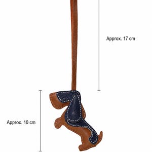 May include: A brown and navy blue leather dog-shaped keyring with white stitching. The keyring is approximately 10 cm tall and 6.5 cm wide, with a brown leather loop. The total length, including the loop, is about 17 cm.
