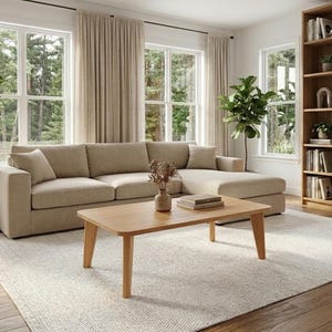 Peut inclure: Salon moderne avec un canapé d'angle beige, une table basse en bois clair et une bibliothèque remplie de livres et d'objets décoratifs. La pièce dispose de grandes fenêtres avec des rideaux neutres et un tapis de couleur claire.