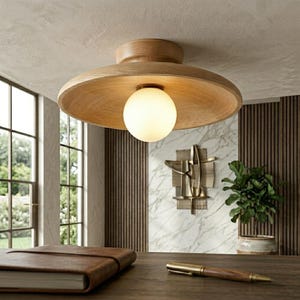 Puede incluir: Una lámpara de techo de montaje empotrado con una base circular de madera clara que muestra un patrón de veta visible. Una bombilla esférica de vidrio blanco esmerilado está centrada bajo el disco de madera, emitiendo una luz suave.