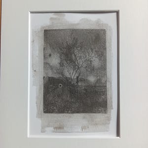 Może przedstawiać: Oprawione, monochromatyczne dzieło sztuki przedstawiające drzewo na polu. Grafika jest w odcieniach szarości i czerni, o fakturze. Dzieło jest oprawione w neutralnym kolorze i oprawione w białą ramę, tworząc minimalistyczną estetykę.